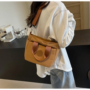 Détail du sac cabas en toile marron avec bandoulière réglable dans un décor de café