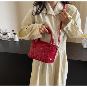 Detail of red quilted bucket bag with white lettering and round handle in a cafe setting