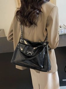 Elegant black glossy tote bag with silver bow accent and chain strap for women