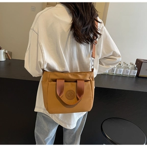 Sac fourre-tout en toile marron avec logo embossé et bandoulière sur le mannequin