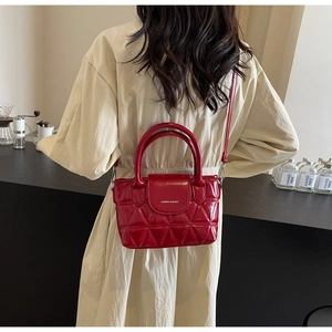 Rear view of a red quilted leather bucket bag with top handles and a slim shoulder strap