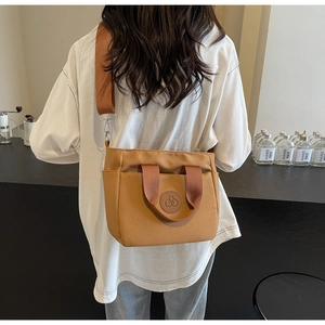 Détail d'un sac cabas en tissu marron chameau avec large bandoulière sur le modèle