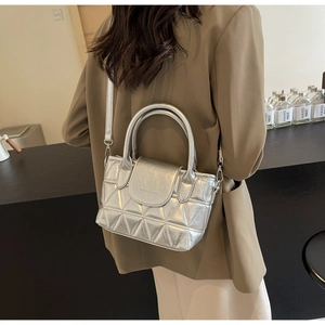 Detailed view of silver quilted bucket bag with metallic finish and top handle on model