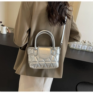 Close-up of silver quilted bucket bag featuring metallic finish and fashion lettering
