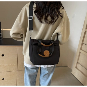 Détail du sac cabas en toile noire avec bandoulière réglable et poches latérales pratiques