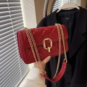 Close-up of red quilted crossbody bag with gold square buckle and chain strap
