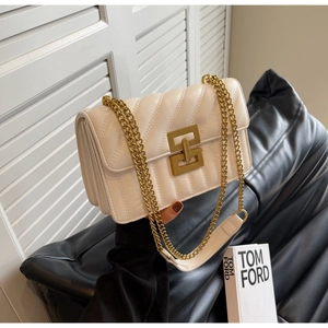 Détail d'un sac à main en cuir matelassé beige avec chaîne dorée et fermoir métallique