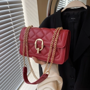 Detailed view of red quilted crossbody bag featuring a golden oval buckle and chain strap