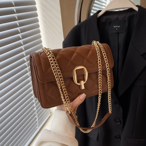 Close-up of brown quilted crossbody bag with gold chain strap and square metal lock