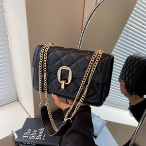 Detail of the black quilted crossbody bag with gold chain strap and D-ring lock detail