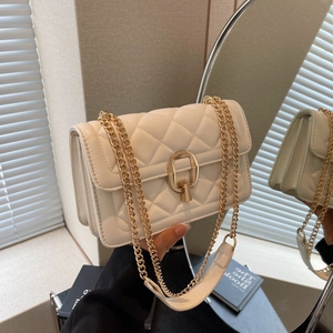 Detail view of cream quilted crossbody bag with gold ring lock and metal chain strap