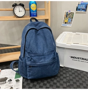 Detail of blue washed denim backpack with spacious pockets and durable fabric texture