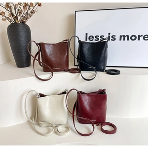 Quattro borse a secchiello nei colori marrone, nero, bianco e bordeaux su base bianca