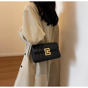 Détail du sac à chaîne noir surpiqué verticalement avec fermoir en métal doré élégant