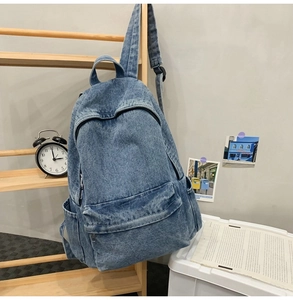 Detail of blue denim backpack with multi-pocket design and washed texture finish