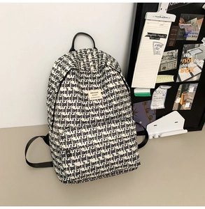Detail of canvas school backpack with all-over black letter print and front zip pocket