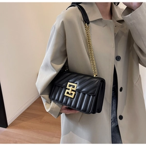 Détail du sac bandoulière en cuir matelassé noir avec fermoir doré et bandoulière chaîne