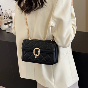 Close-up of black quilted crossbody bag with gold chain strap worn by a model