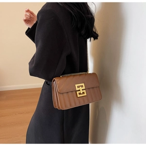 Sac à bandoulière en cuir matelassé marron avec fermoir doré porté par le modèle