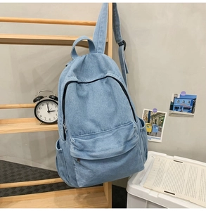 Detail of light blue denim backpack with front flap pocket and adjustable straps