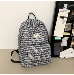 Detail of black and white school backpack with letter prints and MACHUGE brand label