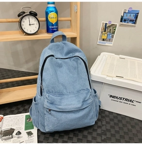 Detailed texture of light blue denim backpack with zipper compartments in a casual setting