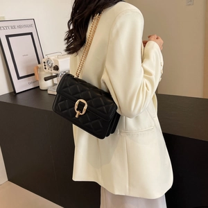 Side view of a model wearing a black quilted leather crossbody bag with gold chain strap