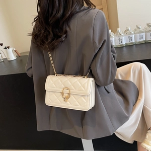Detail of beige quilted crossbody bag with horsebit buckle and gold chain strap