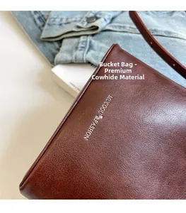 Dettaglio borsa a secchiello in pelle marrone martellata con logo argentato e texture