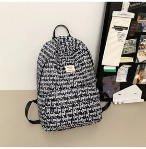 Detail of canvas backpack featuring black and white love of god graffiti print and brand label