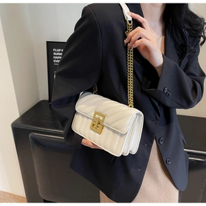 Gros plan détaillé d'un sac bandoulière blanc matelassé avec une chaîne dorée sur un blazer