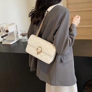 Detail of white quilted faux leather crossbody bag with gold chain strap on model