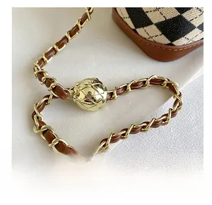 Detail of metal ball adjuster and leather-woven chain on checkered crossbody bag