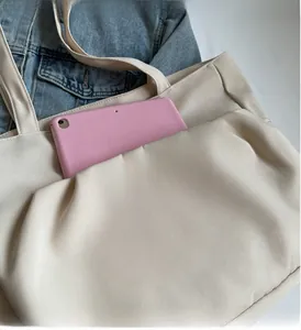 Detail of durable pocket on off-white canvas tote bag holding a pink tablet