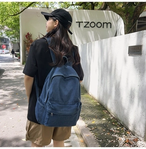 Outdoor street shot of a casual denim backpack with metal zippers and side pockets