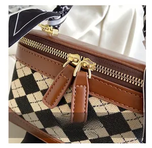 Close-up of golden zipper and checkered fabric on vintage handbag with silk scarf
