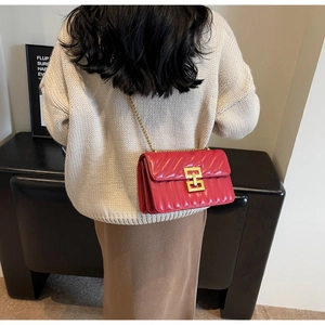 Vue détaillée d'un sac bandoulière matelassé rouge avec chaîne dorée sur un mannequin