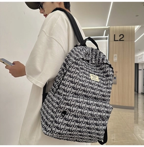 Detail of a large black school backpack with white love of god prints and logo