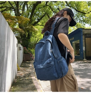 Outdoor street shot of large capacity dark blue denim backpack with side pocket and zippers