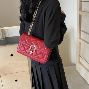 Detail of red quilted chain crossbody bag with golden hardware shown on a model