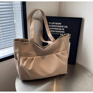 Detailed macro view of beige pleated tote bag showing fabric texture and side pocket