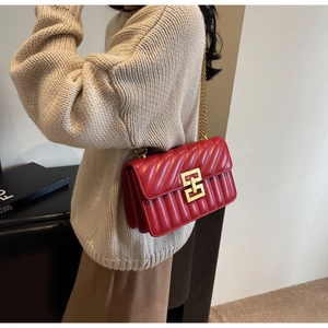 Détail d'un sac bandoulière en cuir rouge matelassé avec boucle dorée géométrique