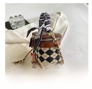 Detail of checkered bucket bag featuring printed silk scarf handle and golden chain strap