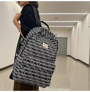 Detail of black canvas backpack with white script print and branded woven label