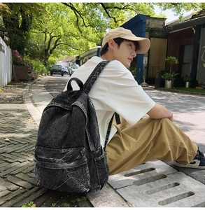Outdoor lifestyle shot of a large retro charcoal denim backpack with acid wash texture