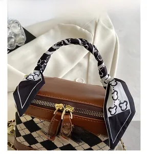 Close-up of leather vanity bag with chain, golden zipper and bear pattern silk scarf handle