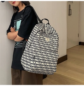 Detail of white canvas backpack with black letter print and brand label on shoulder