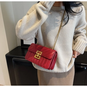 Détail d'un sac bandoulière en cuir rouge matelassé avec chaîne dorée sur mannequin