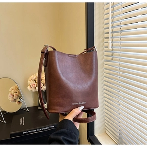 Dettaglio ravvicinato di una borsa a secchiello marrone in ecopelle con logo argentato