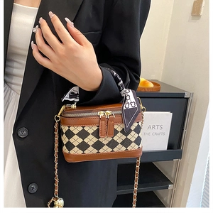 Brown leather crossbody bag with chain strap and scarf wrap worn with black blazer